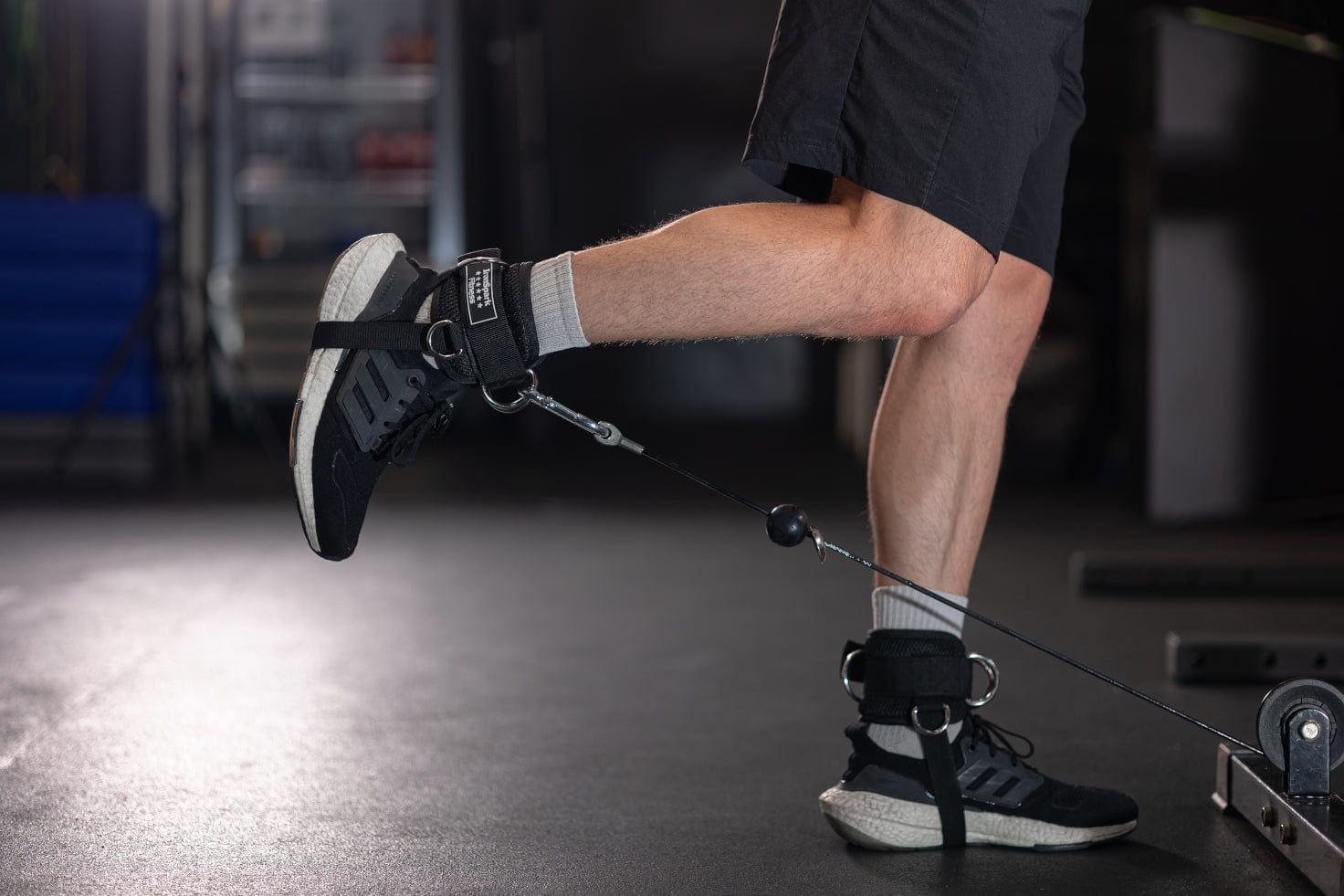 Athlete doing reverse leg raise wearing IronSpark Fitness ankle strap attached to a cable machine